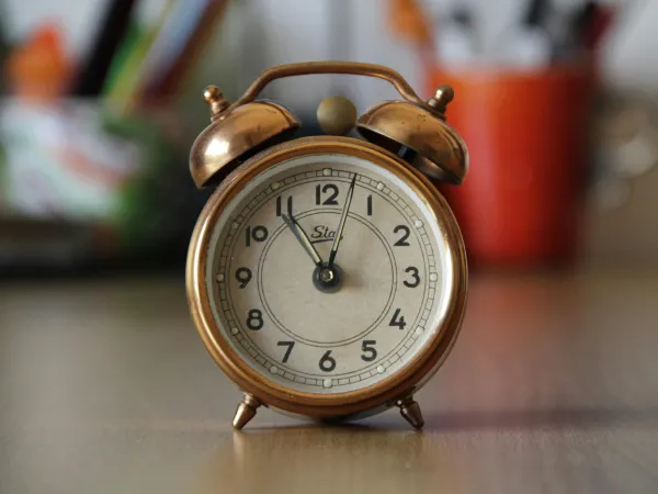 Ein goldfarbener Wecker, der auf einem Tisch steht.